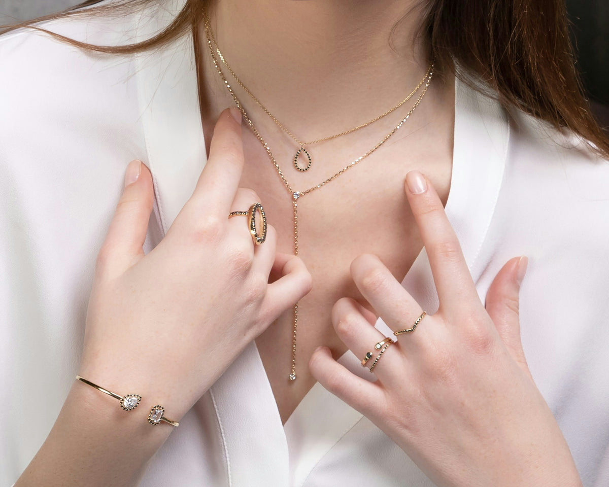 Close-up of a woman wearing stacked rings and a fine necklace